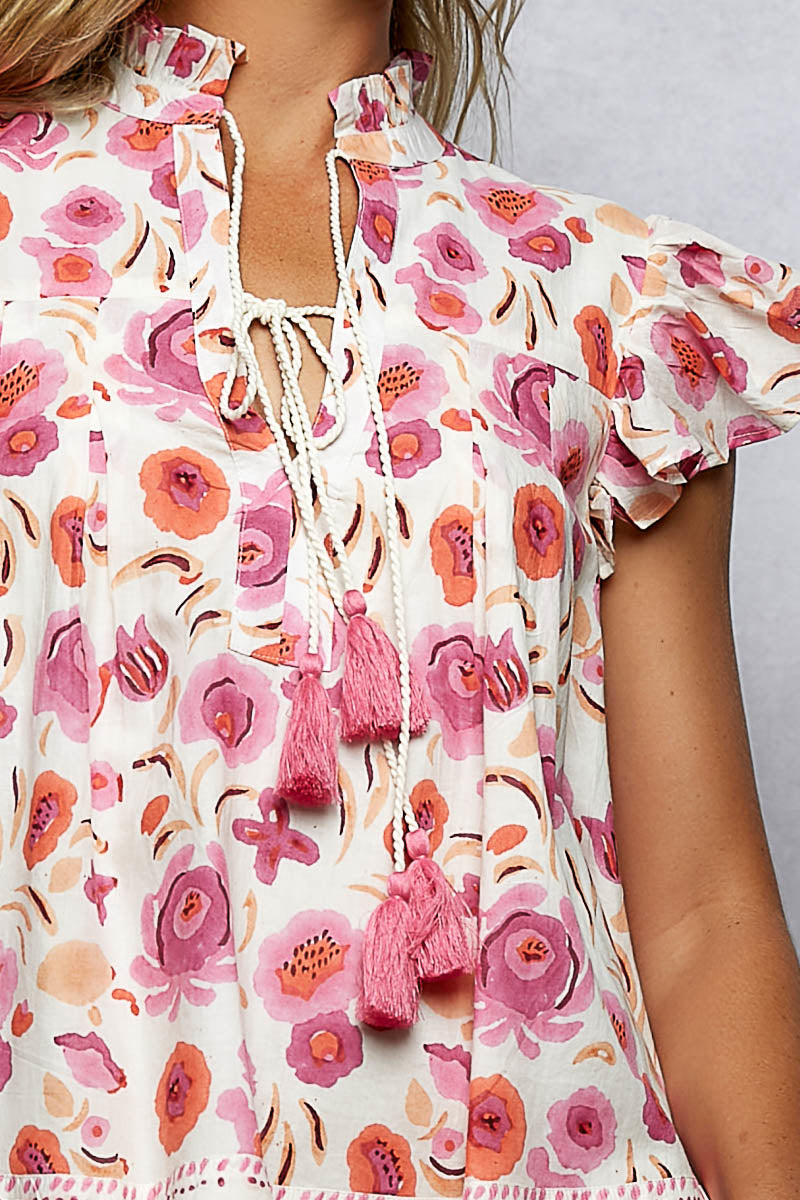Floral blouse with pink tassels on a neutral background