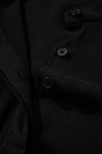 Close-up of a black coat with buttons on a dark background