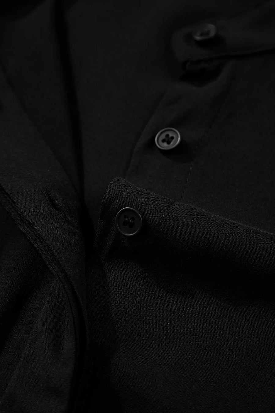 Close-up of a black coat with buttons on a dark background