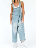 Person wearing light blue denim overalls on a white background