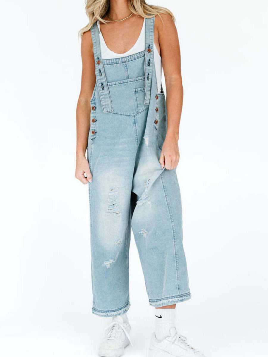 Person wearing light blue denim overalls on a white background