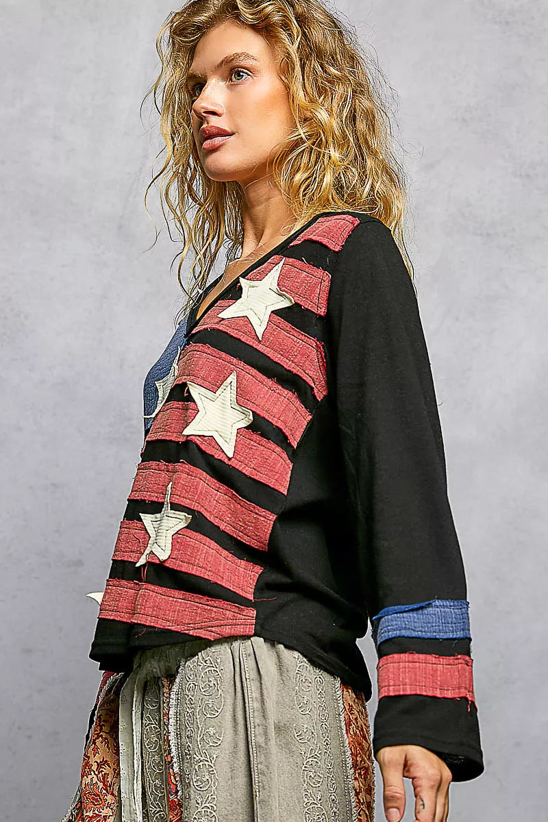 Woman wearing a black sweater with red and blue pattern and white stars on a gray background