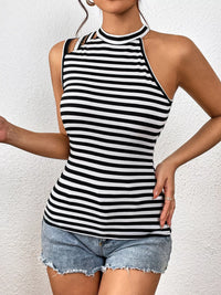 Woman wearing a black and white striped halter top with denim shorts against a white background