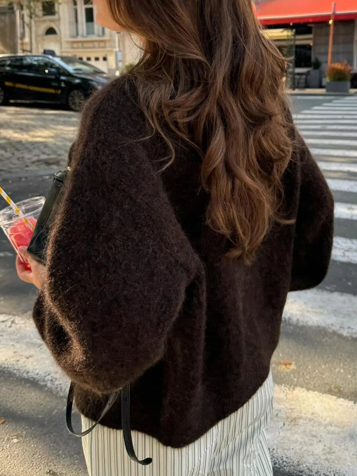 Person wearing a brown fuzzy jacket on a city street
