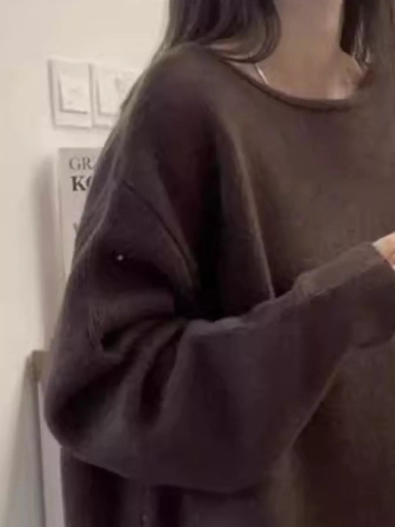 Person wearing a dark brown oversized sweater indoors.