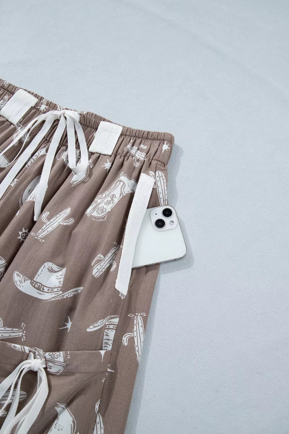 Brown shorts with white patterns and a phone on a light gray background