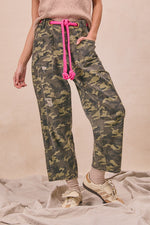Camouflage pants with pink drawstring worn by a person on a beige background