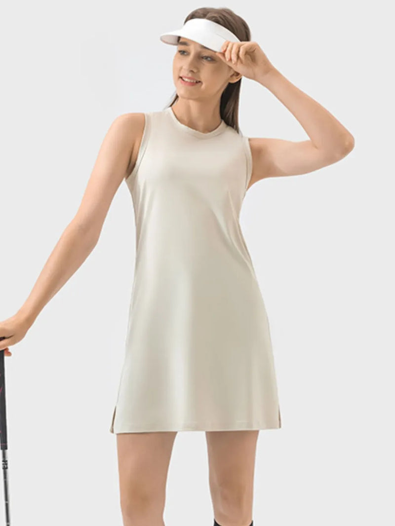 Woman wearing a beige sleeveless dress and white visor on a light gray background