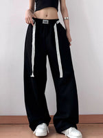 Person wearing black wide-leg pants with white drawstrings on a plain background