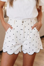 White shorts with black polka dots worn by a person indoors.
