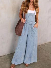 Woman wearing denim overalls with a plain background