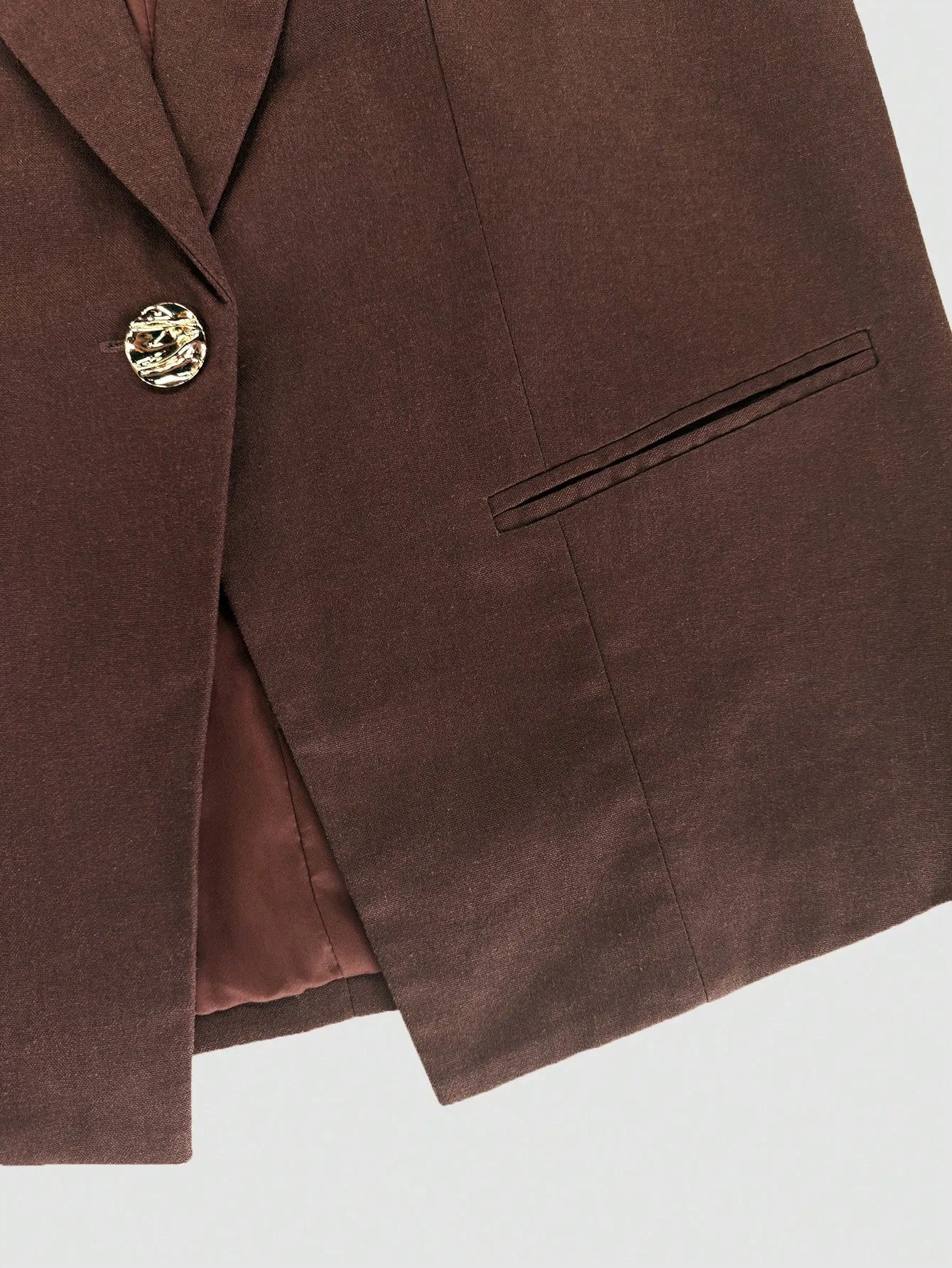 Brown blazer with a gold button on a light gray background