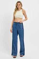 Woman wearing a white crop top and blue jeans on a white background