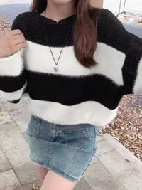 Person wearing a black and white striped sweater with a denim skirt outdoors.