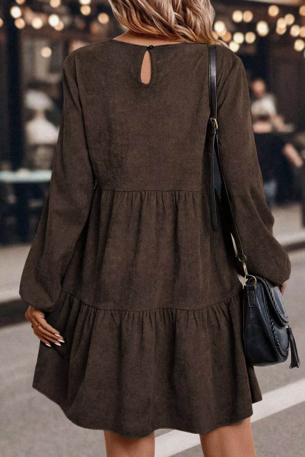 Woman wearing a brown dress with a black bag in an indoor setting