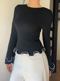 Person wearing a black long-sleeve top with white trim and white pants.