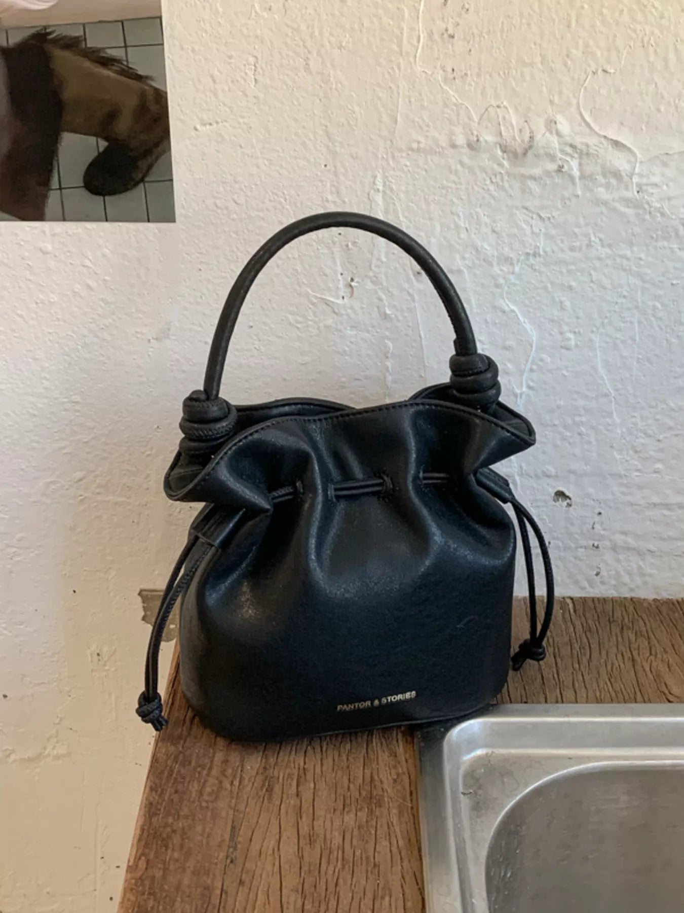 Black leather handbag on a kitchen counter with a white wall background