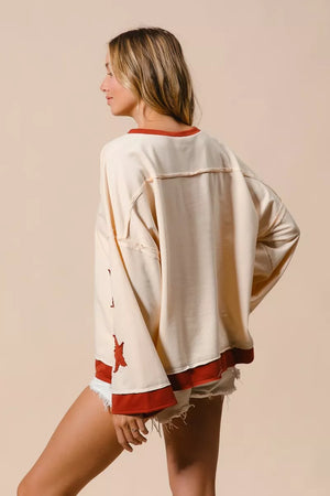 Woman wearing a beige sweatshirt with red accents and shorts on a beige background