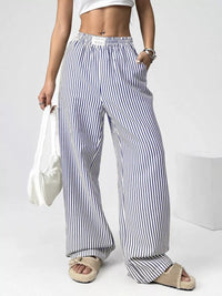 Person wearing blue and white striped wide-leg pants on a plain background