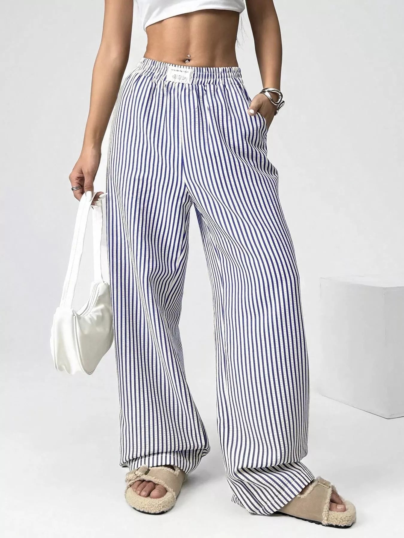 Person wearing blue and white striped wide-leg pants on a plain background