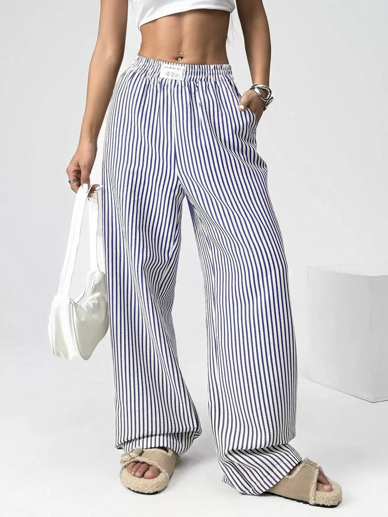 Person wearing blue and white striped wide-leg pants on a plain background