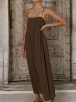 Woman wearing a brown jumpsuit standing in front of a wooden door.