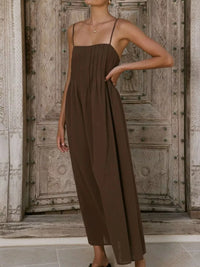 Woman wearing a brown jumpsuit standing in front of a wooden door.