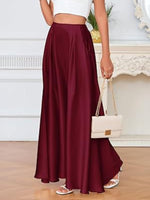 Person wearing a burgundy skirt and white top, holding a white handbag indoors.
