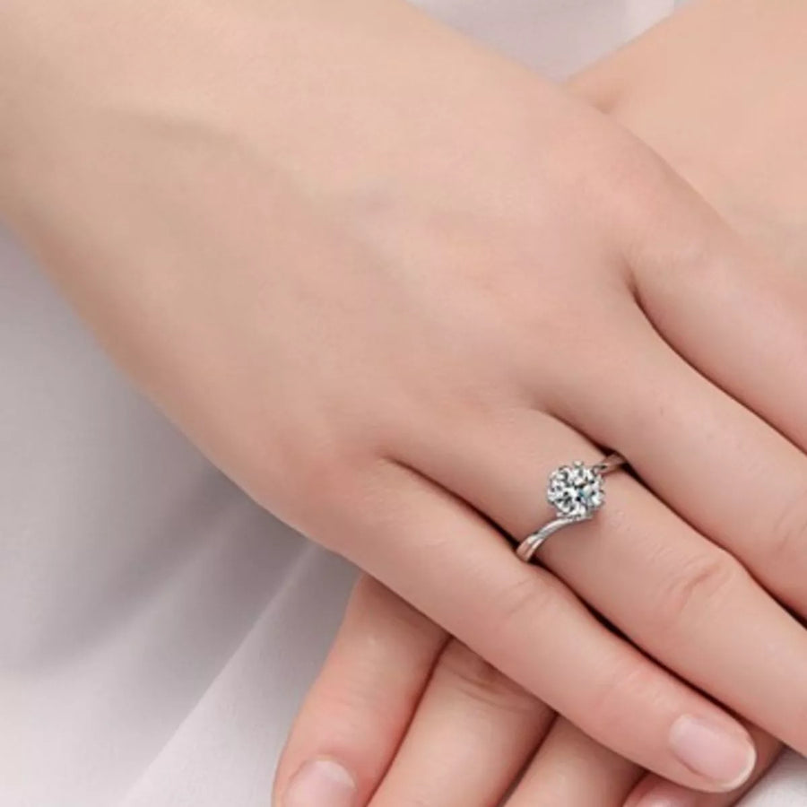 Silver ring with a diamond on a person's finger against a light background