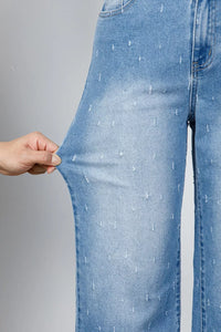 Close-up of blue jeans being stretched with a hand on a gray background