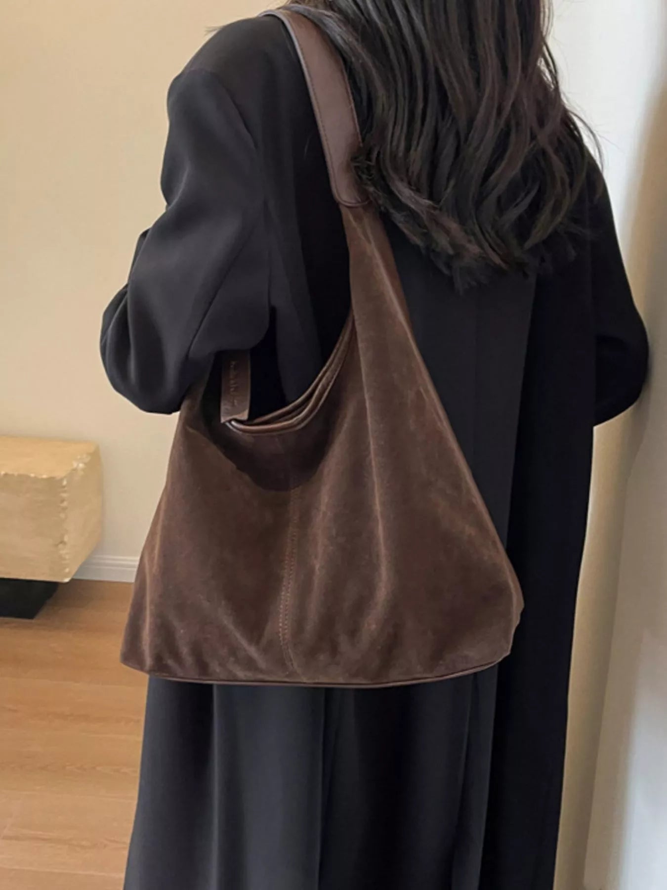 Person wearing a brown shoulder bag indoors