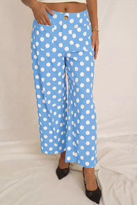 Blue pants with white polka dots worn by a person on a light gray background