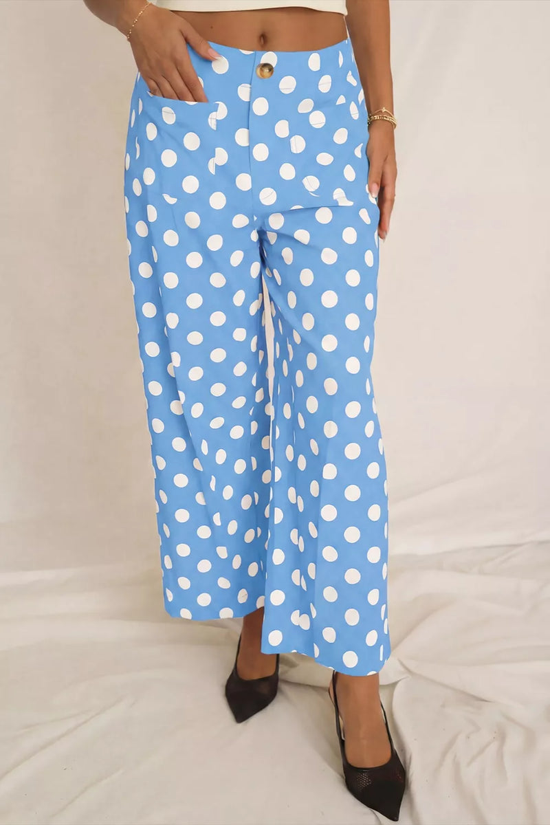 Blue pants with white polka dots worn by a person on a light gray background