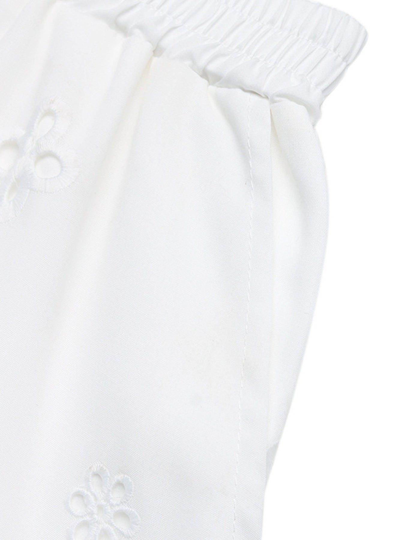 Close-up of a white textured fabric with a subtle pattern on a white background