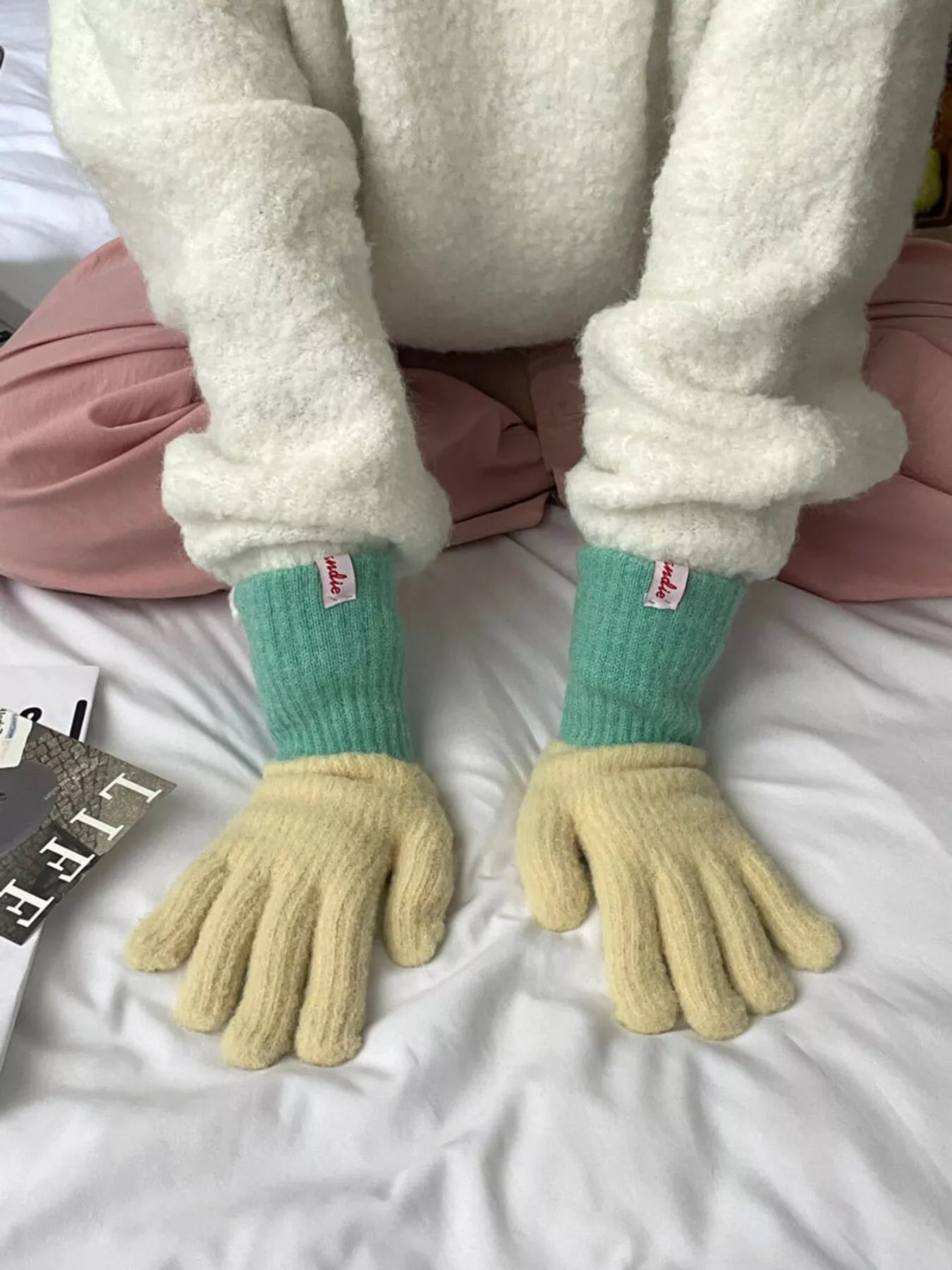 Person wearing green socks with yellow cuffs and gloves on a white surface.