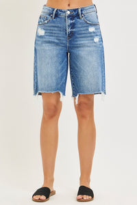 Blue denim shorts worn by a person on a plain background