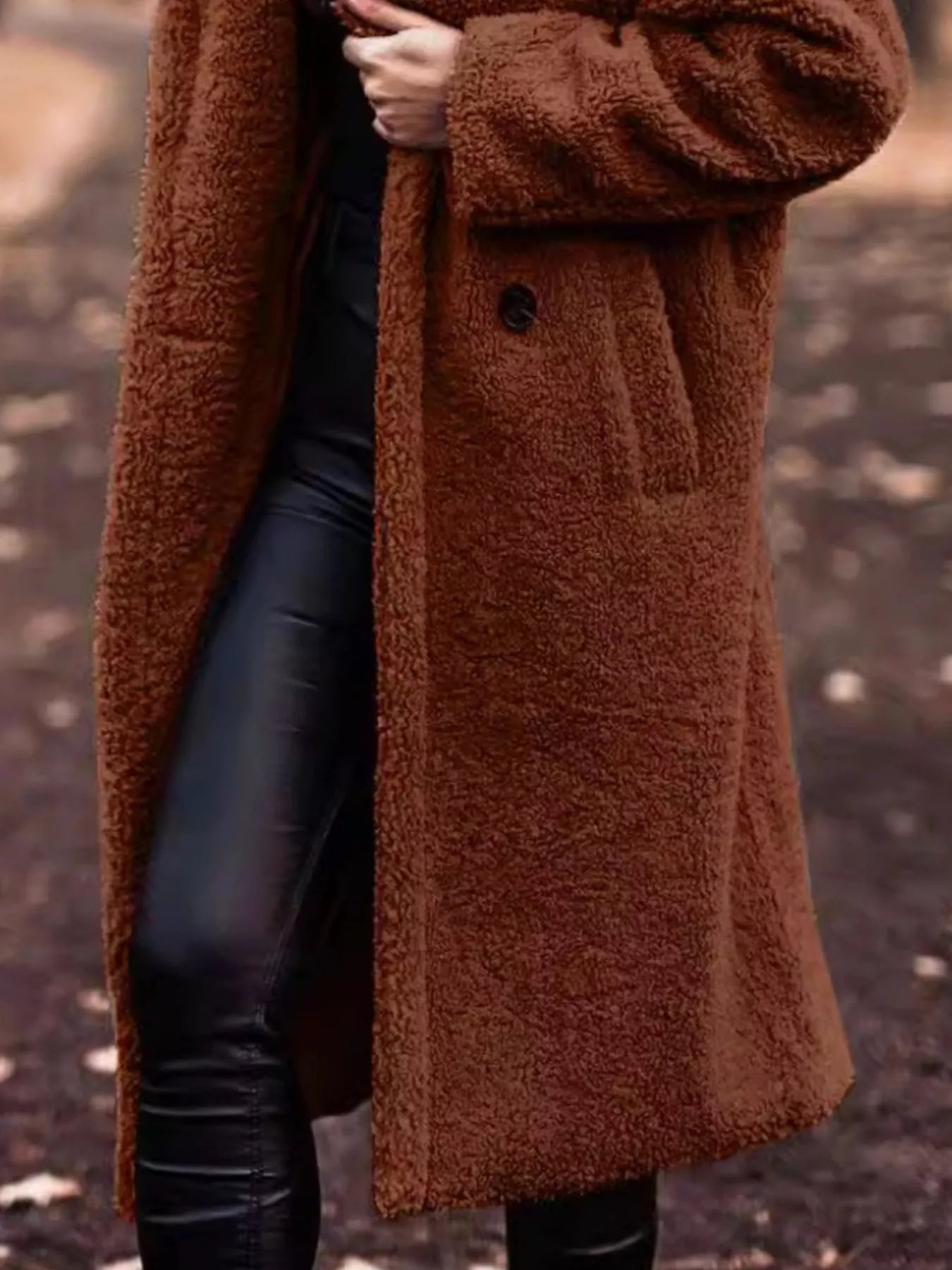 Brown teddy coat worn by a person with a blurred background