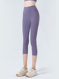 Person wearing purple leggings and white sneakers on a light gray background