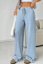 Person wearing blue and white striped pants with a neutral background