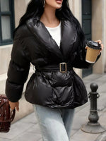 Person wearing a black puffer jacket holding a coffee cup on a city street.
