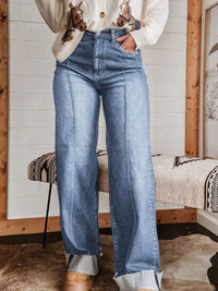 Person wearing blue jeans standing in a room with wooden walls and a bench.