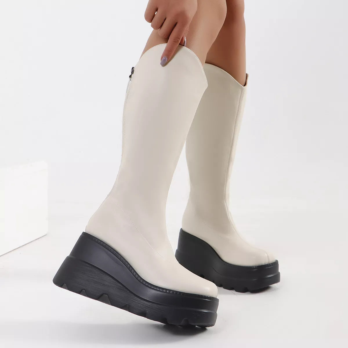 White knee-high boots with black soles on a white background