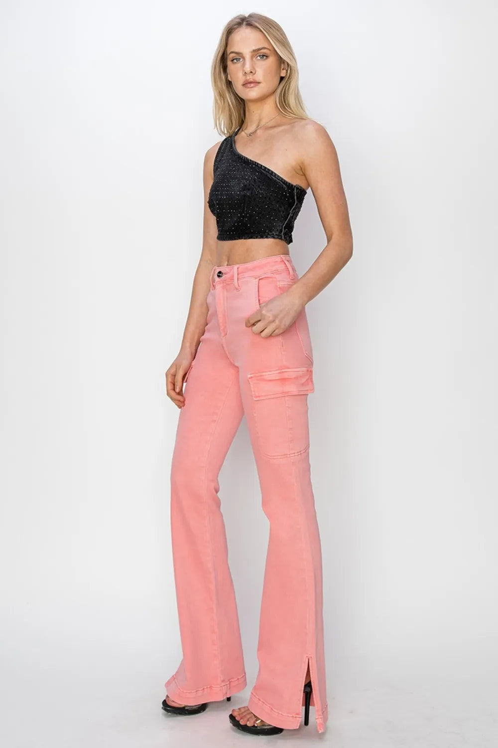 Woman wearing a black crop top and pink flared jeans on a white background