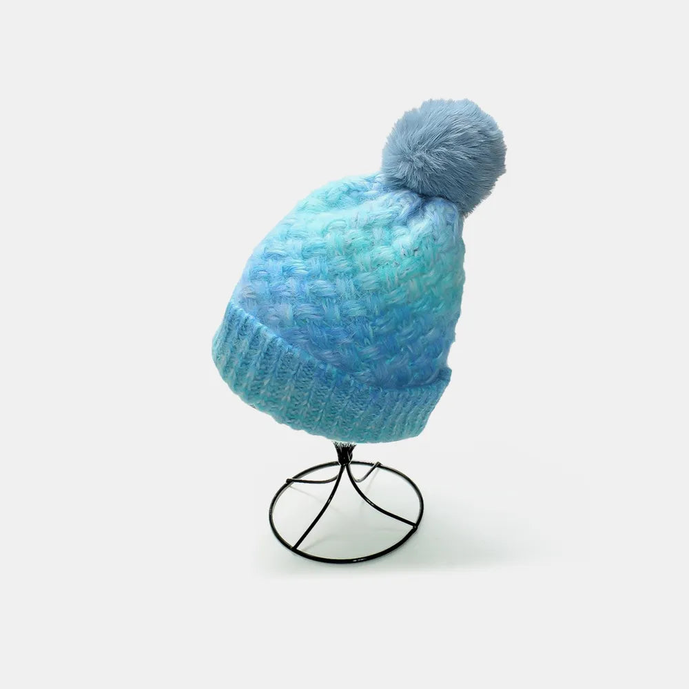 Blue knitted beanie with a pom-pom on a white background