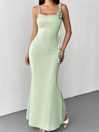 Woman wearing a light green evening gown with floral details on a white background