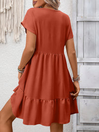 Person wearing a rust-colored dress against a light wooden panel background