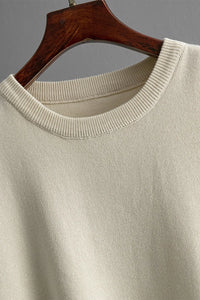 Beige sweater on a wooden hanger against a gray background