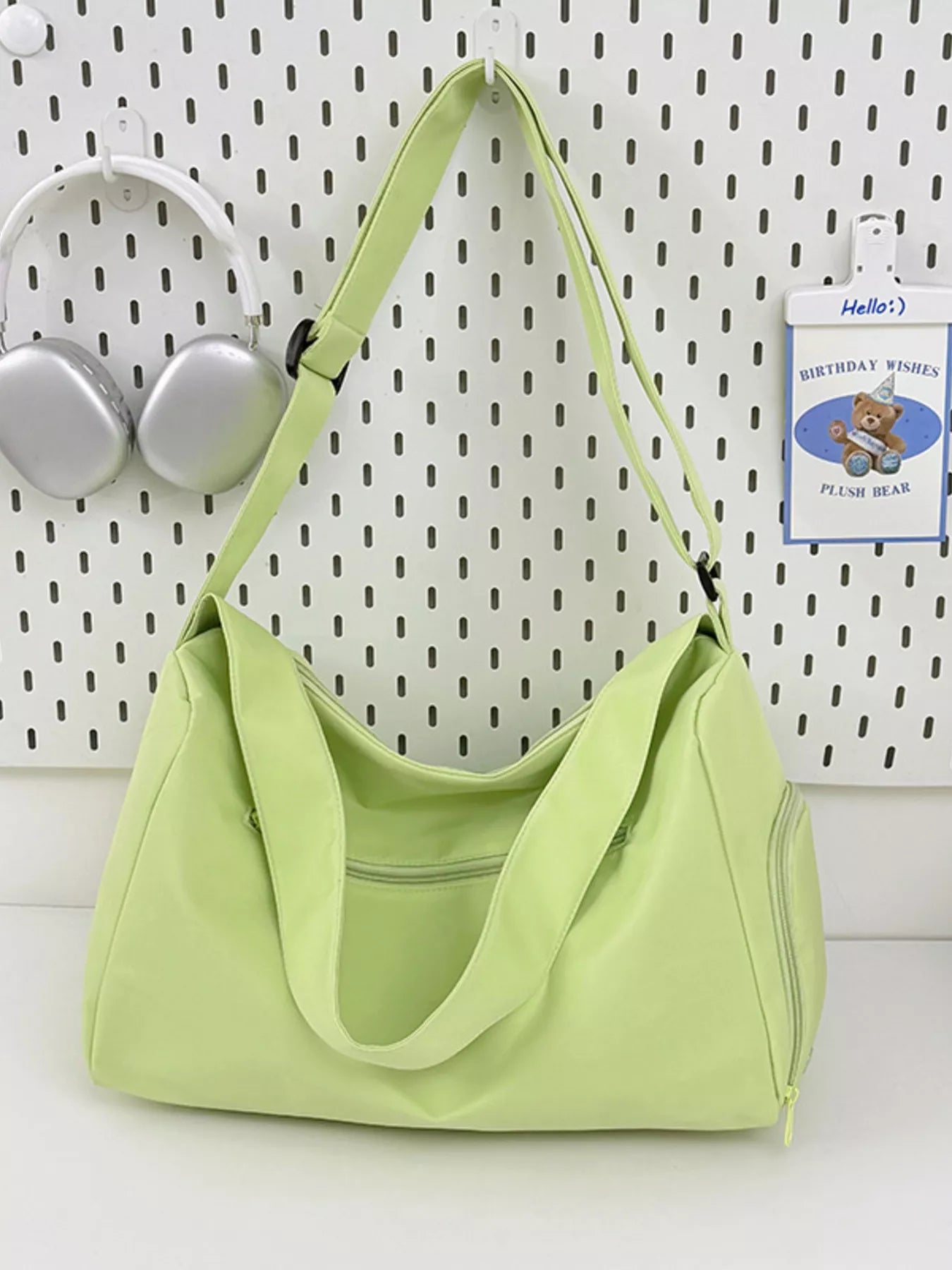 Light green handbag on a white surface with a white wall background
