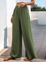 Person wearing green wide-leg pants standing on a tiled floor.
