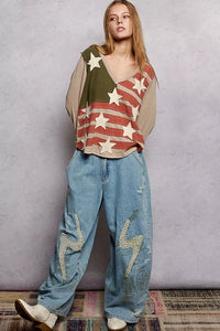 Person wearing a flag-themed top and distressed jeans against a plain background